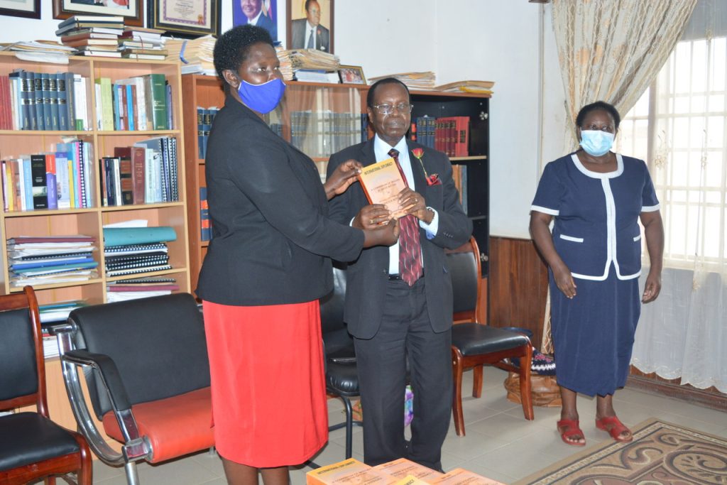Amb Butagira handing over his book to the Prof. Maud Kamatenesi Mugisha VC BSU