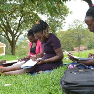 Undergraduate students engaged in a discussion group in gardens above the Faculty of Education, Arts and Media Studies, Bishop Stuart University