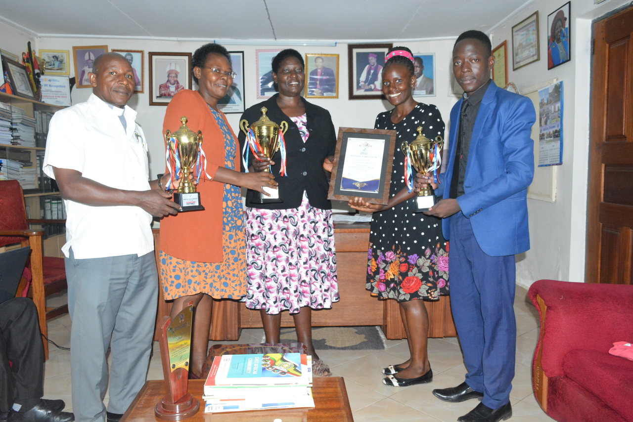 The VC, Prof. Maud Kamatenesi Mugisha (3rd L) and PRO team receive a certificate of participation and trophies attained during the FEAUS Games from the Female Sports Tutor, Ms. Nambowa Sarah (2nd R)